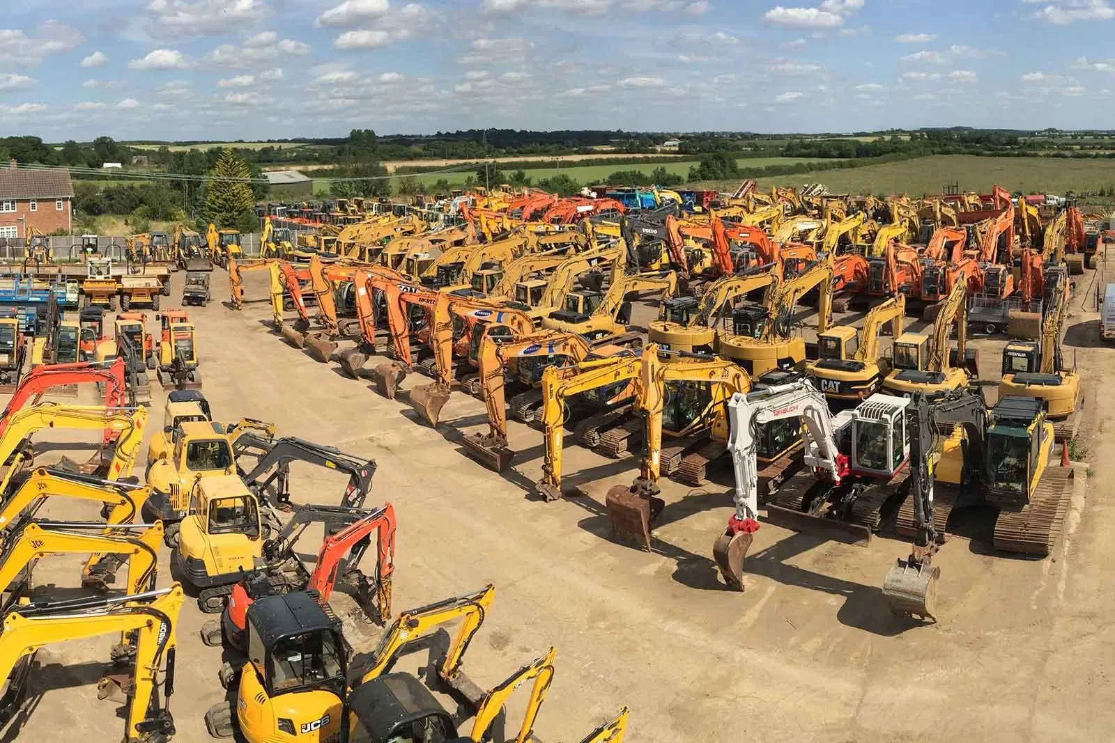 Aerial view of an equipment yard with rows of excavators